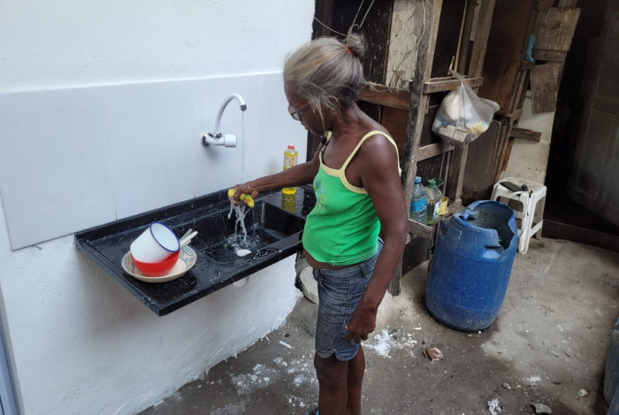 Na foto maior, a moradora na nova cozinha dá um trato na louça, que antes era lavada no quintal (ao lado)
